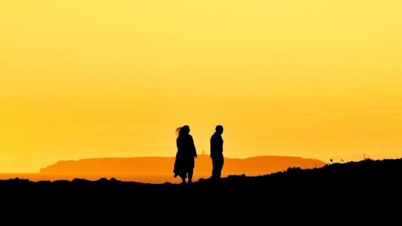 A couple on a hill watching a sunset