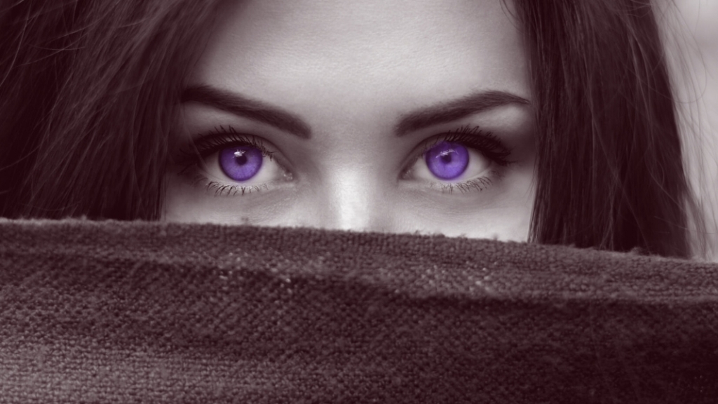 Woman with violet eyes hiding behind a darkened linen cloth.