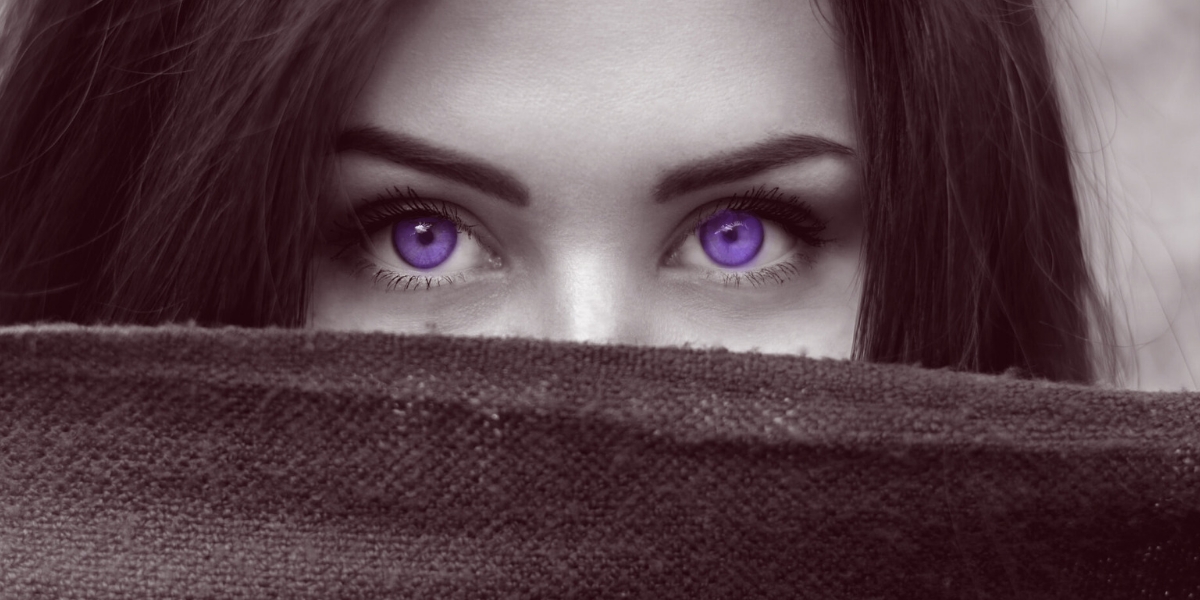 Woman with violet eyes hiding behind a darkened linen cloth.